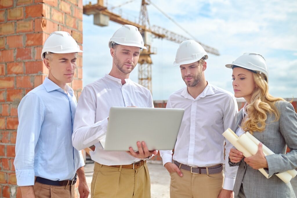 Woman and men looking at laptop at construction